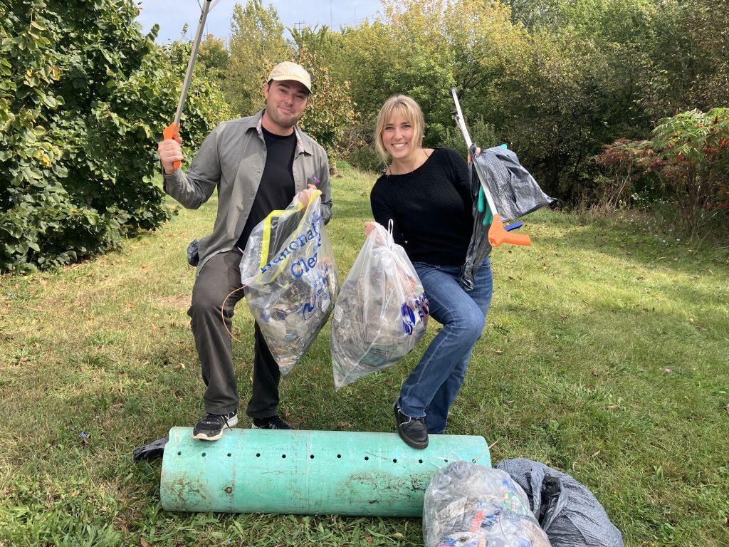 Rotaract Club of Milwaukee members holding bags of trash collected during a river cleanup event